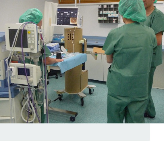 Photo showing three people testing a life-size mockup of a Sophi device in a surgery room-like environment.
